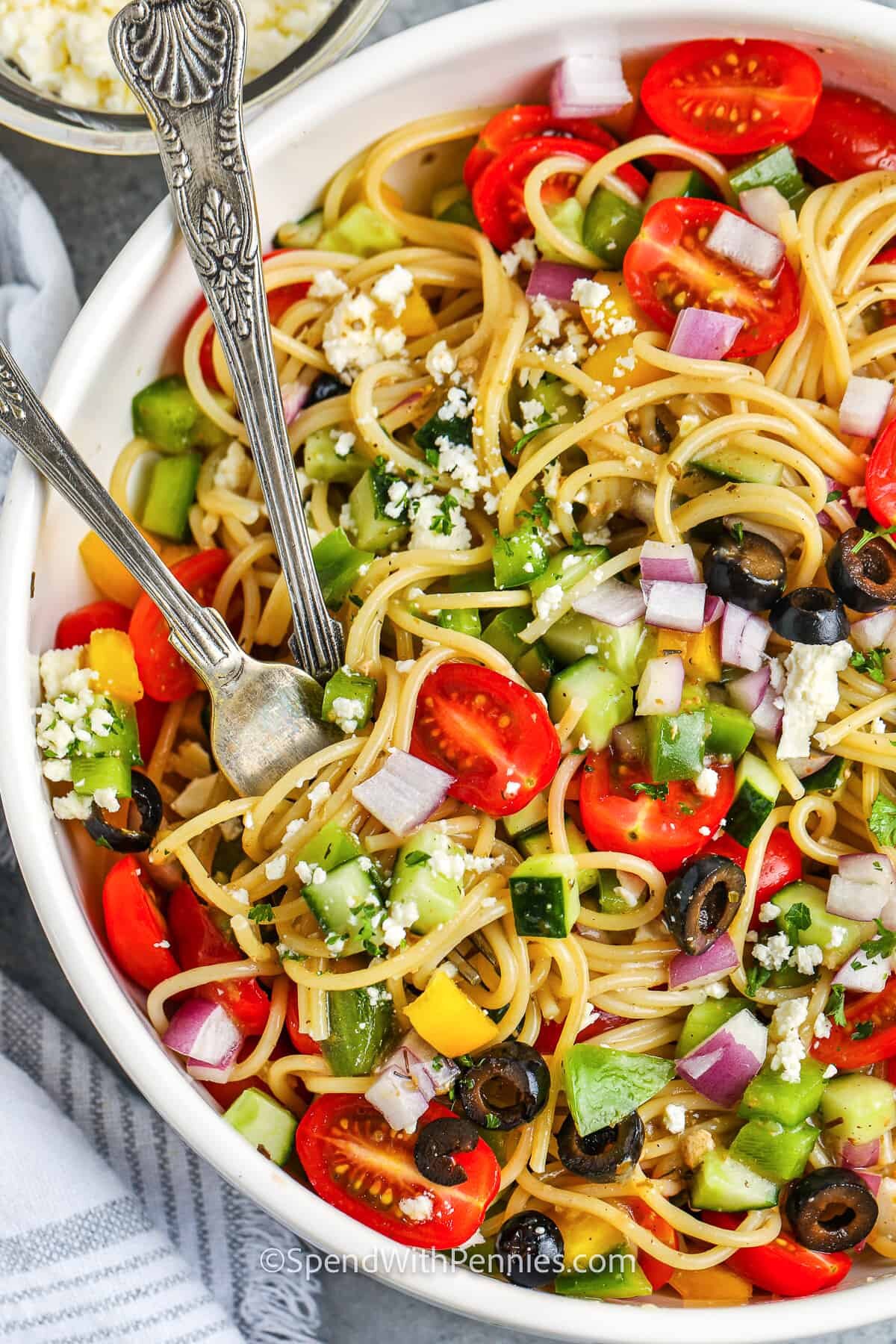 Spaghetti salad in a white bowl with feta cheese