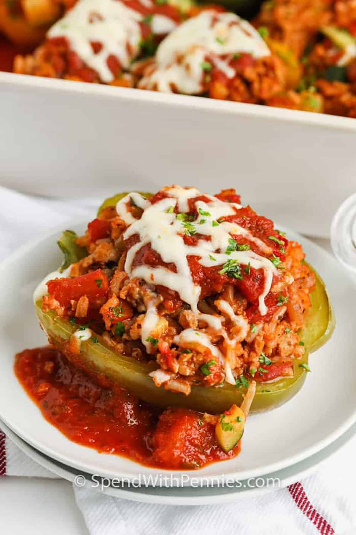 Ground turkey stuffed peppers on a plate with cheese and sauce 