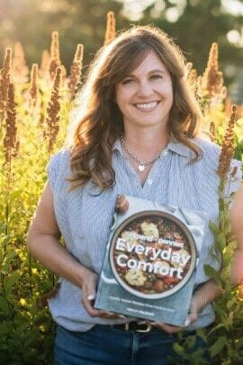 Holly Nilsson from Spend with Pennies holding a copy of her book Everyday Comfort