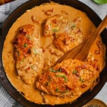 pan of Marry Me Chicken with a wooden spoon taking a piece out